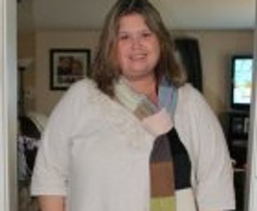 Smiling woman in a white top and multicolored scarf indoors.