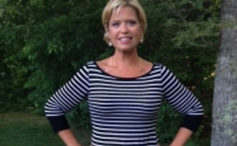 Woman in a striped shirt standing outdoors with hands on hips.