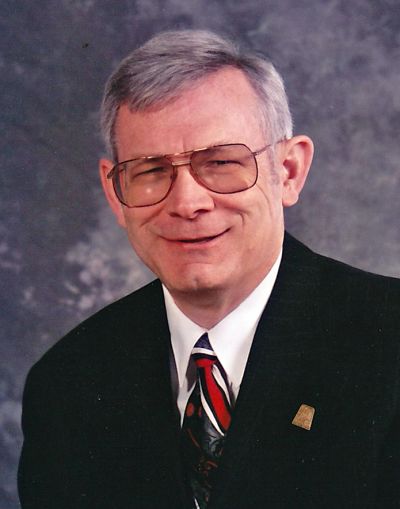 Smiling older man in suit and glasses.