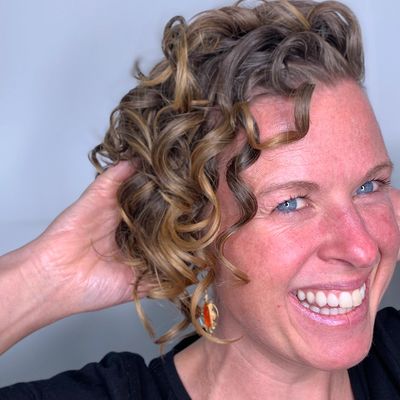 Happy smiling woman with hands in her curly hair
