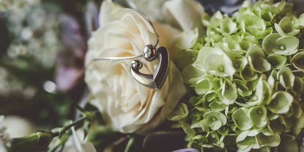 Bouquet of wedding flowers up close with heart shaped necklace draped over a white rose