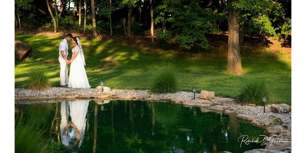 Bride and groom holding hands beside picturesque koi pond