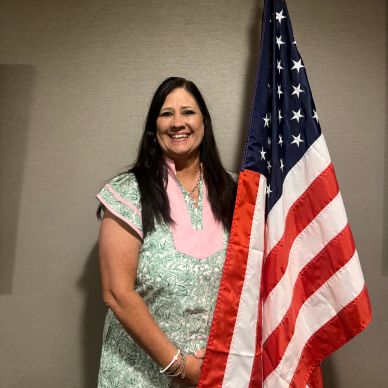 Woman smiling next to an American flag.