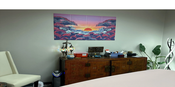 Serene therapy room with massage table, decorative lamp, and vibrant wall art.