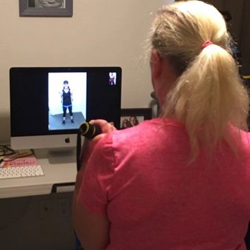 A woman exercises at home following a virtual workout on her computer.