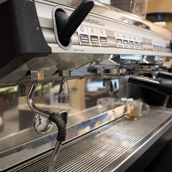 Close-up of a professional espresso machine with steam wand and control buttons.