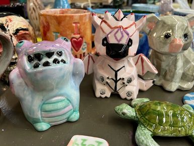 Cute ceramic animal figurines including a purple monster, dragon, dog, and turtle.