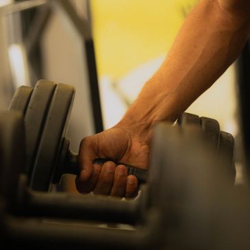 Hand gripping a dumbbell at the gym.