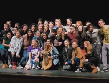 Group photo of diverse people on stage with a trophy.