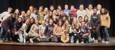 Large group photo on stage with a dog.