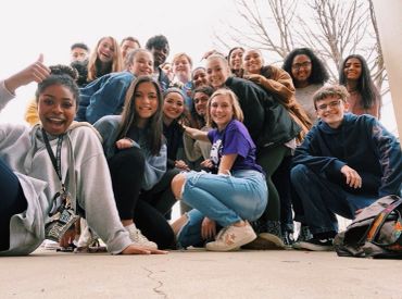 A cheerful group of teenagers posing together outdoors.