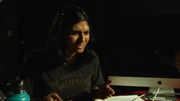 Woman in dim light expresses confusion or frustration.