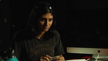 Focused woman holding a phone in a dimly lit room.