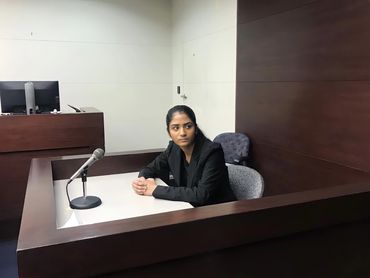 A woman sitting in a courtroom witness stand.