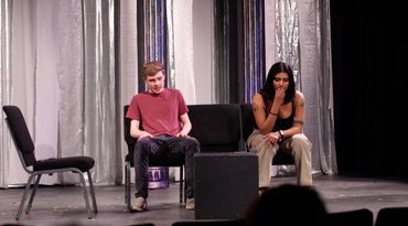 Two people sitting on a stage.