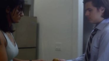 Two people exchanging an item indoors.