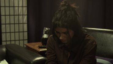A woman sitting with her head down in a dimly lit room.