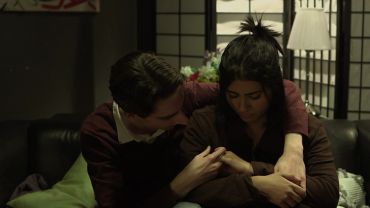 A comforting moment between two people on a couch.