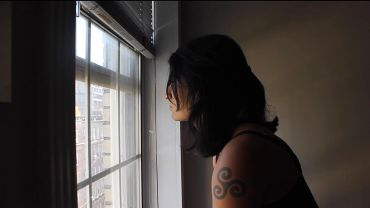 Woman looking pensively out of a window.