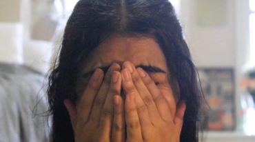 Young woman covering her face with hands.