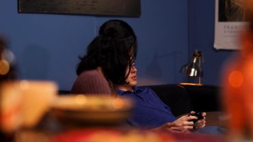 A couple sitting closely on a couch, the man using a phone.