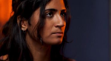 A woman with dark hair looking thoughtfully.