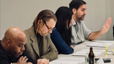Four people focused on reading documents at a meeting table.
