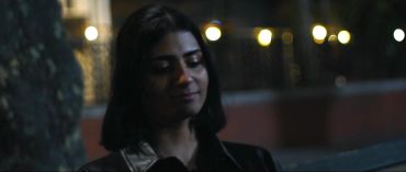 A woman with closed eyes in dim light.
