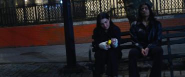 Two people sitting on a bench at night.