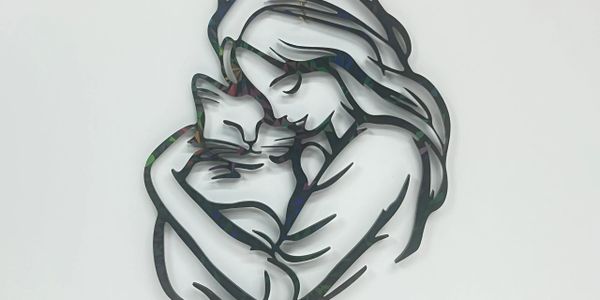Metal art of a woman lovingly holding a cat.