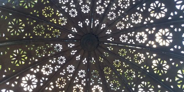 Intricate circular pattern with floral cutouts on a dome ceiling.