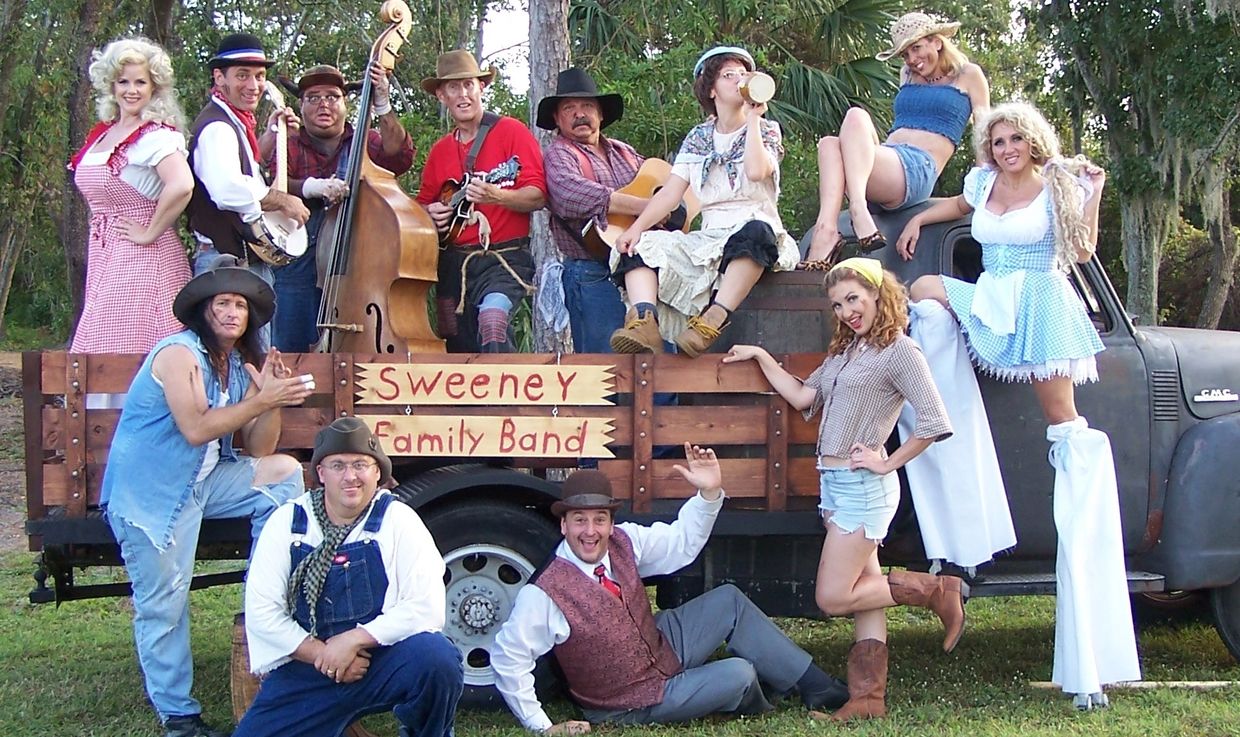 Group photo of Sweeney Family Band in country-themed attire beside a truck.