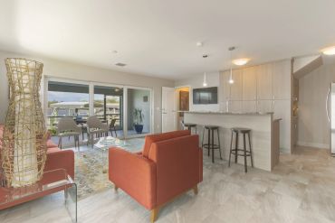 Modern open living room with red chairs and kitchen bar stools.