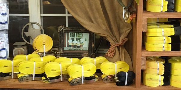 Organized yellow polyester strapping rolls and packaged hardware on wooden shelves.
