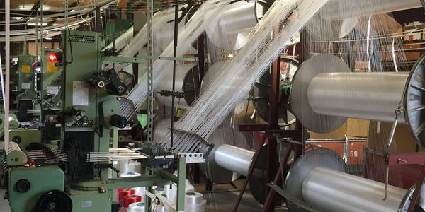 Industrial textile machinery weaving threads in a factory.