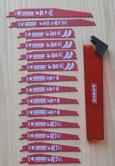 Various Diablo saw blades and a red blade holder on a wooden surface.