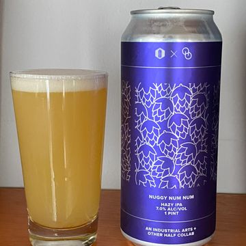 A can of hazy IPA beer next to a glass filled with hazy beer.