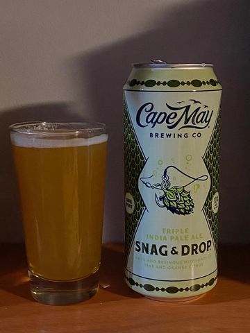 A glass of beer next to a Cape May Brewing Co. Snag &amp; Drop IPA can.