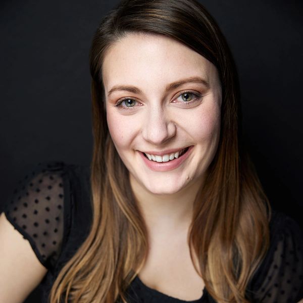 Hayley San Fillippo smiles at the camera in front of a charcoal background.