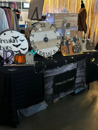Halloween-themed wooden decorations and clocks displayed on a black table.