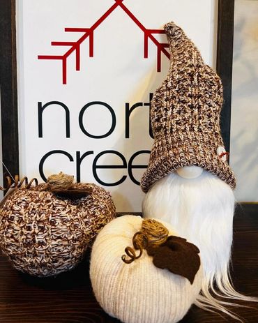 Cozy fall decorations featuring a gnome and knitted pumpkins.