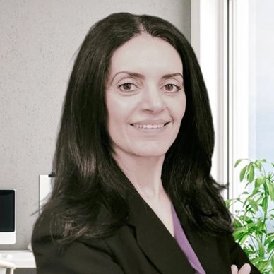 Professional woman with long dark hair smiling confidently in an office setting.