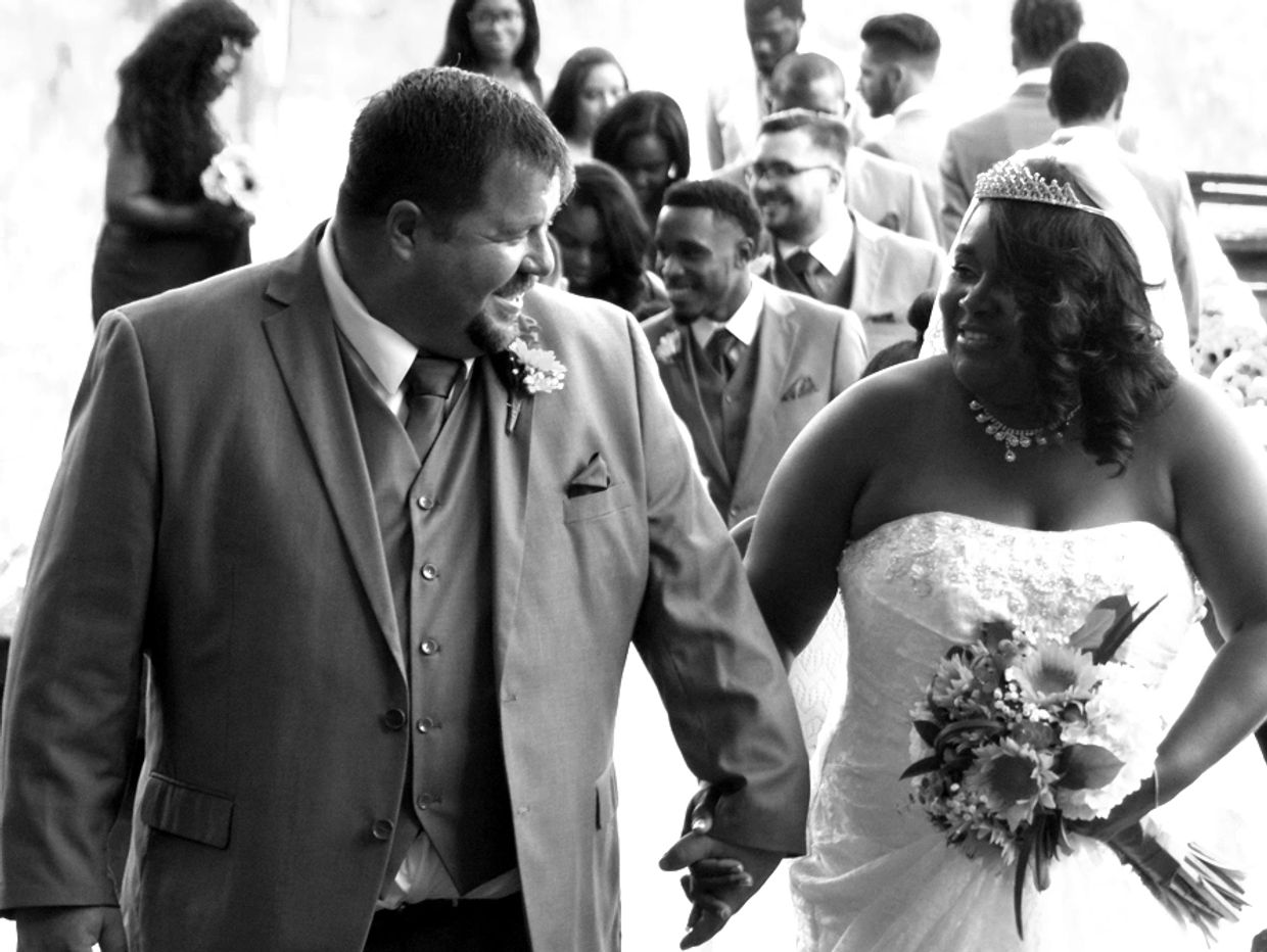 Black and white interracial couple at their wedding. Holding Hands