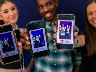 3 smiling people holding cell phones with their Photo Booth  image on each phone