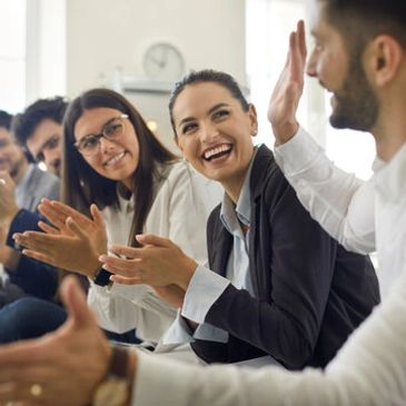 Colleagues smiling and applauding in a professional setting.