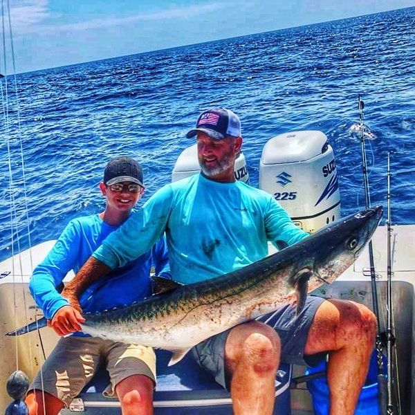 Captain Brad Segree and boy holding fish offshore