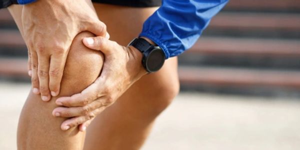 Person holding injured knee with both hands.