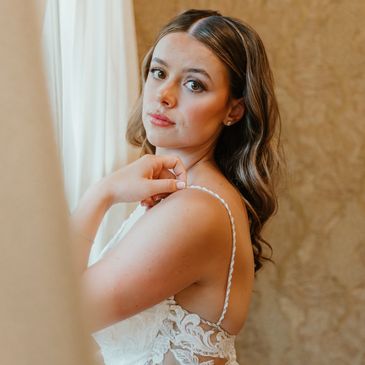 Woman in a white lace dress posing indoors.