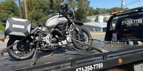 A Moto Guzzi motorcycle secured on a flatbed tow truck.