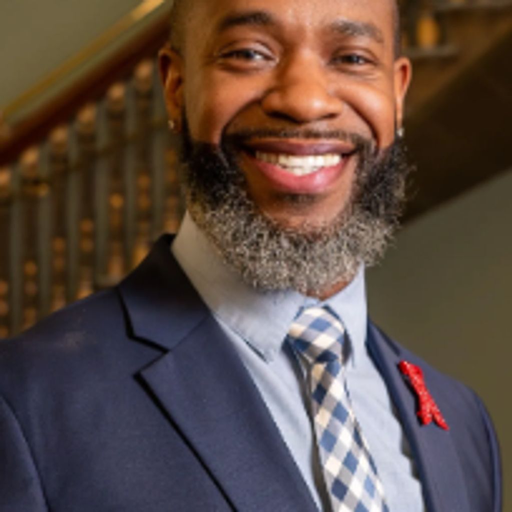 Smiling man with a salt-and-pepper beard in a suit and tie.